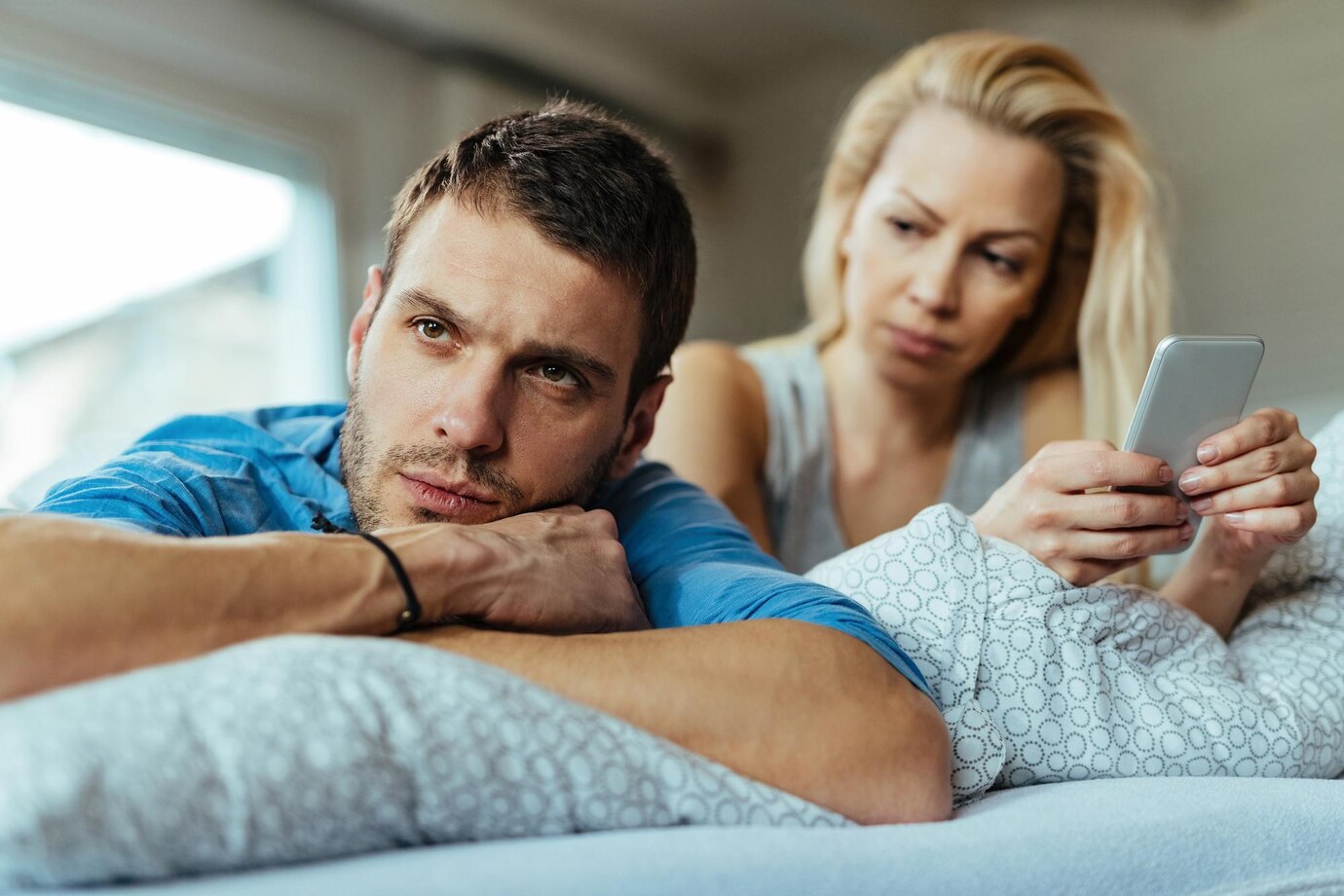 displeased-man-lying-bed-ignoring-his-girlfriend-who-is-text-messaging-mobile-phone_637285-2948.jpg